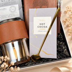Close-up of the glass cup with leather sleeve, hot cocoa, gold spoon and journal